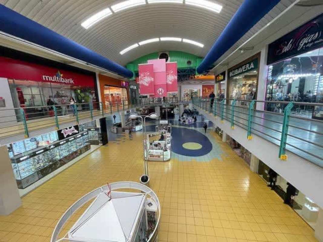 View of Albrook Mall interior featuring kiosks surrounded by retail stores under curved ceiling Panama City