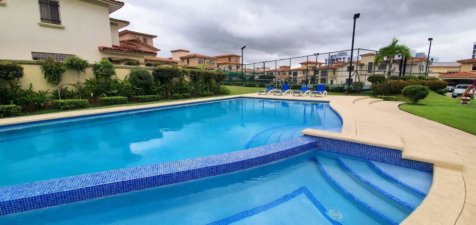 Shared outdoor pool with lounge chairs at Condado del Rey gated community