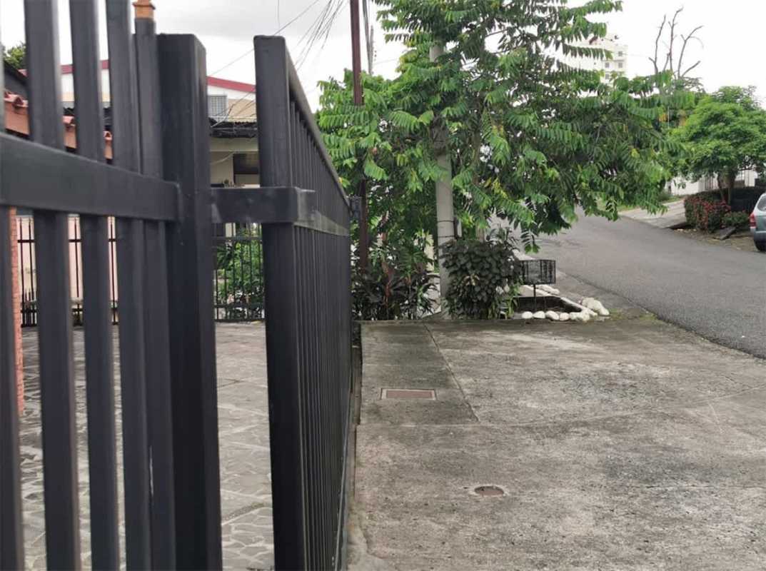 Private backyard with grassy lawn, patio, banana plants, and stone wall in Club X Bethania Panama