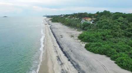 Aerial view of luxury estate with red tile roofs, pool, gardens along Panama coastline