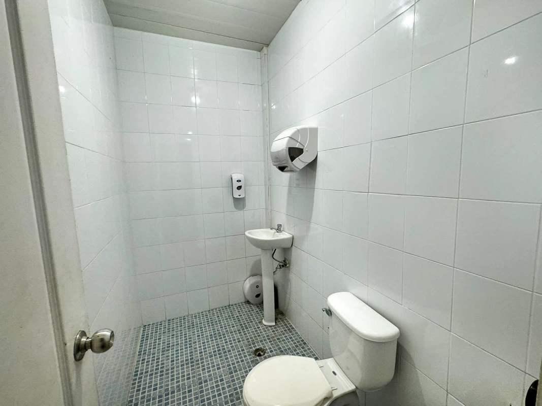 Simple bathroom with white tiled walls and sink inside industrial warehouse in Parque Industrial Las Americas Panama
