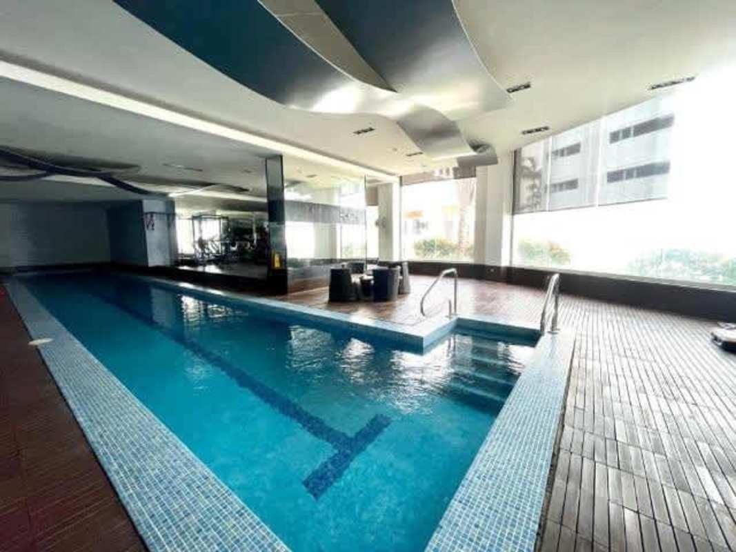 Indoor pool with wood deck, gym area, large windows overlooking city in PH Loft Four 41 Punta Pacifica