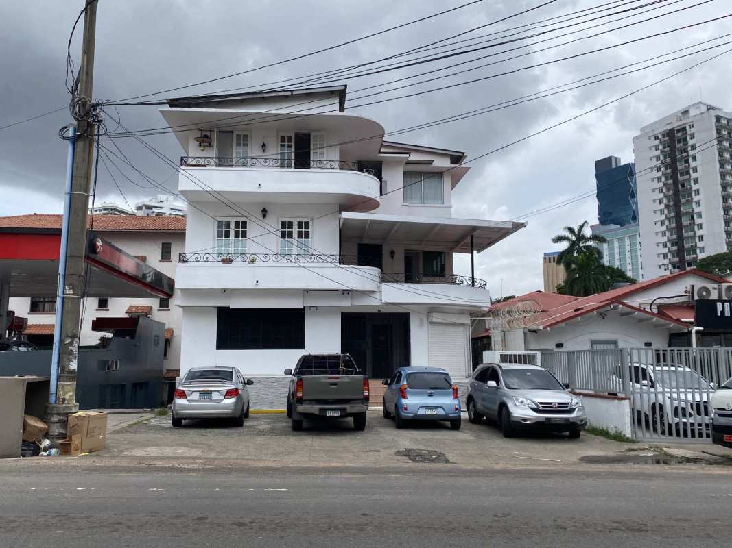 Three-story white mixed-use building with curved balconies and parking spaces, Bella Vista Panama