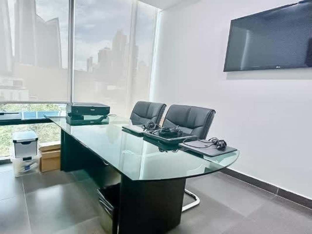 Modern private office space with glass desk, chairs, large window city skyline view in Obarrio Panama