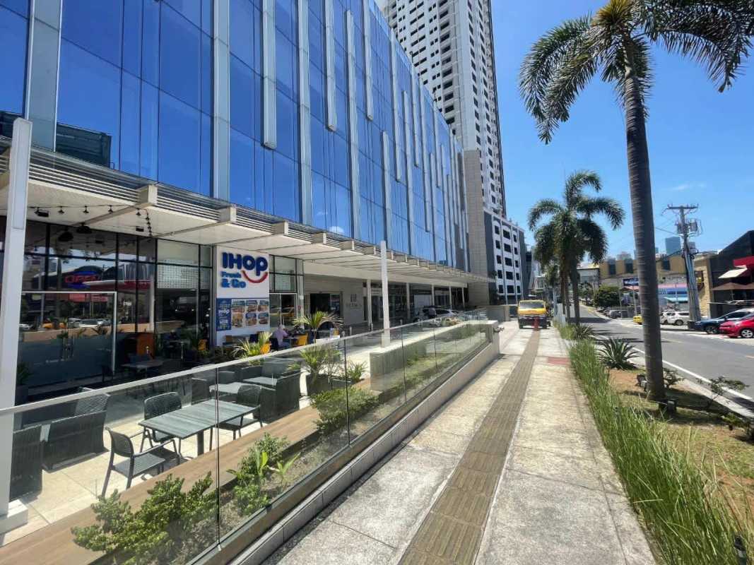 Exterior with palm trees, modern glass walls, outdoor seating at PH Tower Business Plaza in San Francisco Panama