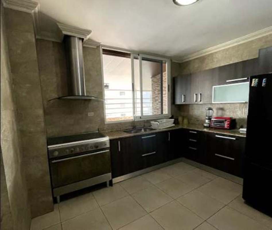 Kitchen with wood cabinets, granite countertops, marble style tile in PH Torre Marbella Panama