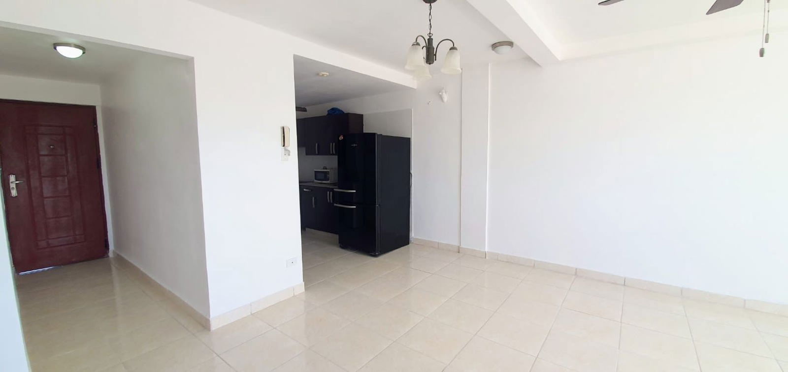 Living area open to kitchen with refrigerator microwave ceiling fan PH Madison Towers Condado del Rey