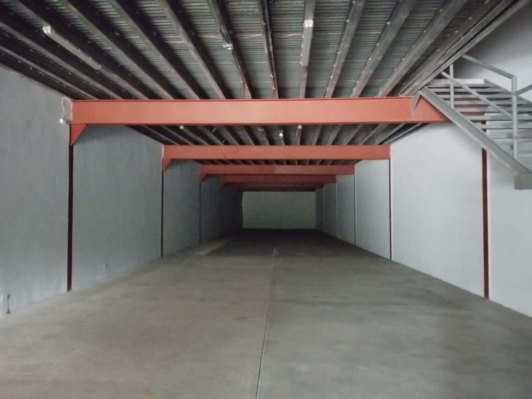 Spacious empty warehouse interior with steel beams, concrete flooring, mezzanine and staircase at Juan Díaz Panama