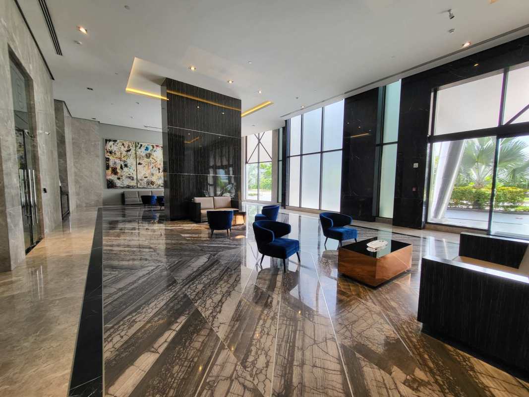 Spacious lobby with marble floors, blue seating and large windows at Empire Residences Panama