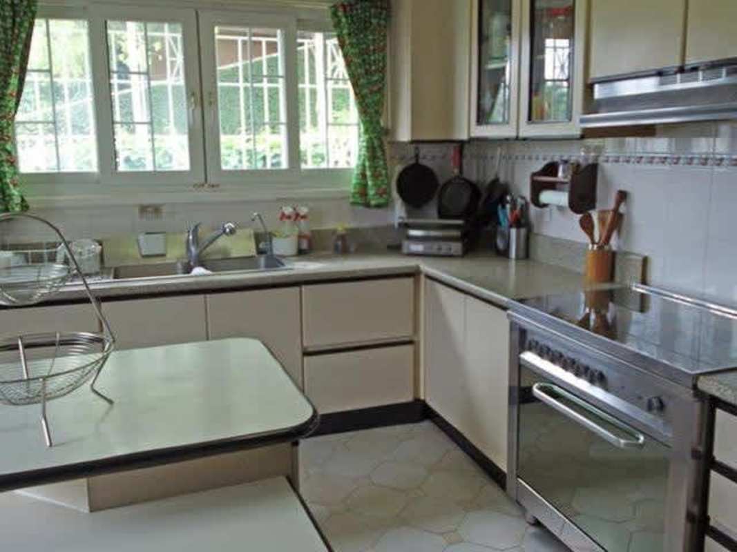 Spacious kitchen with traditional cabinets, island, stainless appliances and large window in luxury Dos Mares home