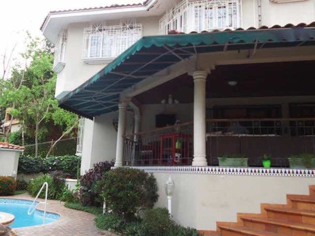 Exterior view of two-story Mediterranean house with balcony, pool, and landscaping in Dos Mares Panama