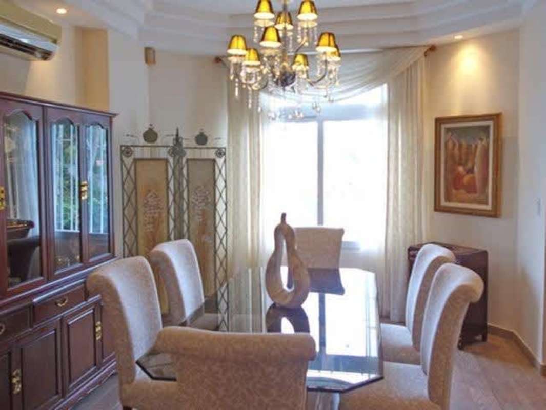 Traditional dining room with chandelier lighting, upholstered chairs, large window in Dos Mares Panama estate