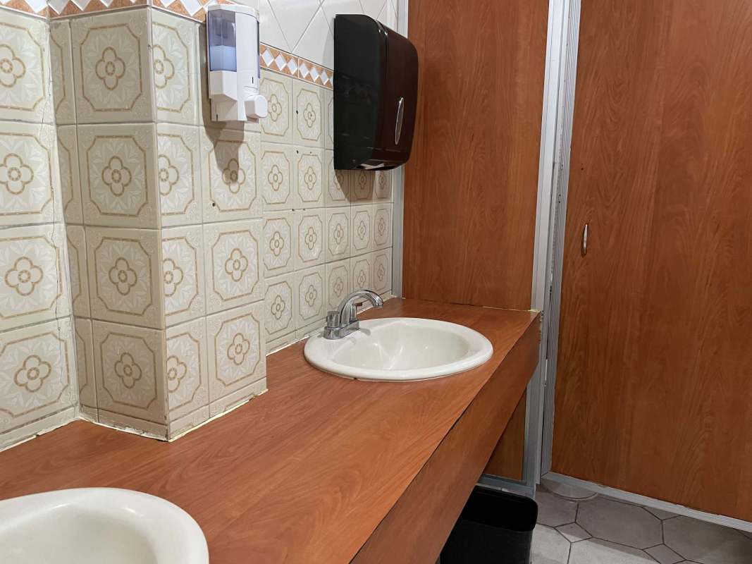 Double sink restroom with patterned tiles and wood accents in commercial property Panama