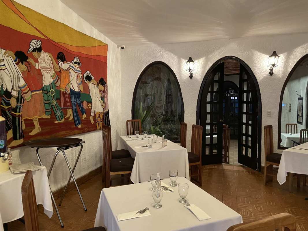 Rustic restaurant dining with colorful mural, arched windows, and wooden decor in Panama City