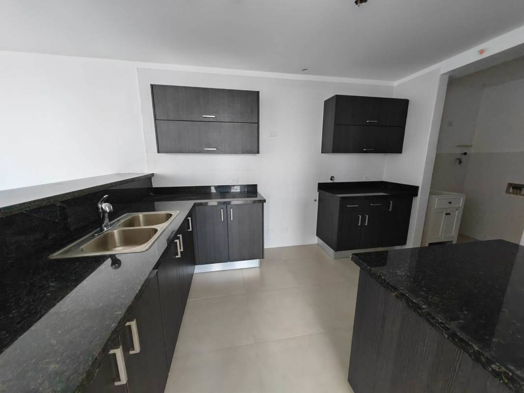 Modern kitchen with granite countertops, breakfast bar, dark cabinetry in PH Country Heights new apartment Panama