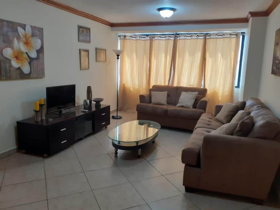 Apartment living room with beige sofas, large window, and tile flooring PH Torre Ebelle Bella Vista Panama