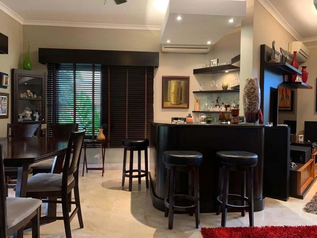 Outdoor covered terrace with dining area, BBQ, view of garden and pool in Antigua Costa del Este Panama