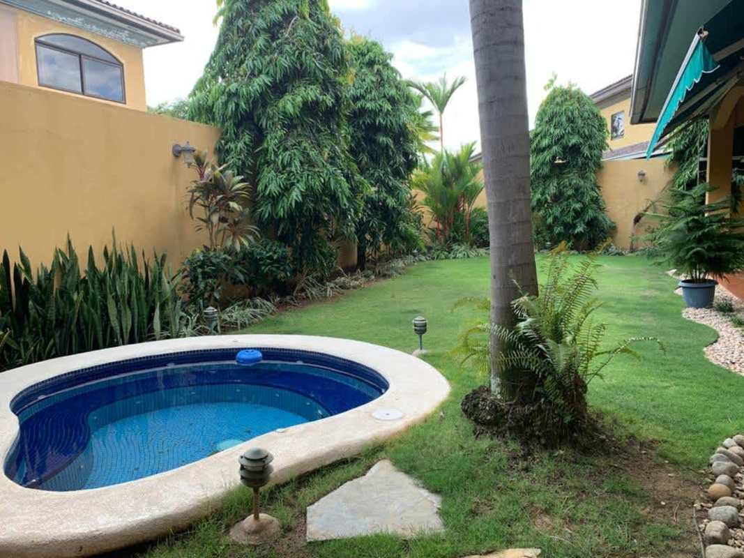Private tropical backyard with tiled plunge pool, lawn, garden and privacy walls in Antigua Costa del Este Panama