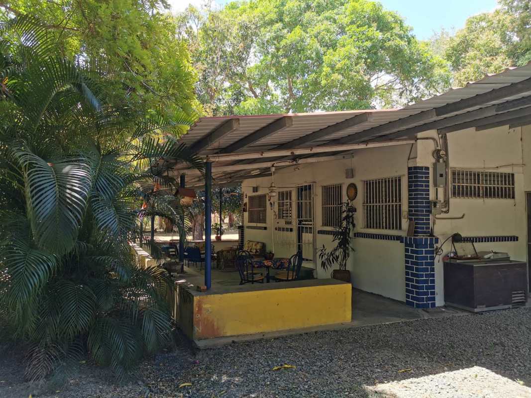 White exterior of countryside beach home with covered patio and lush tropical plants Panama