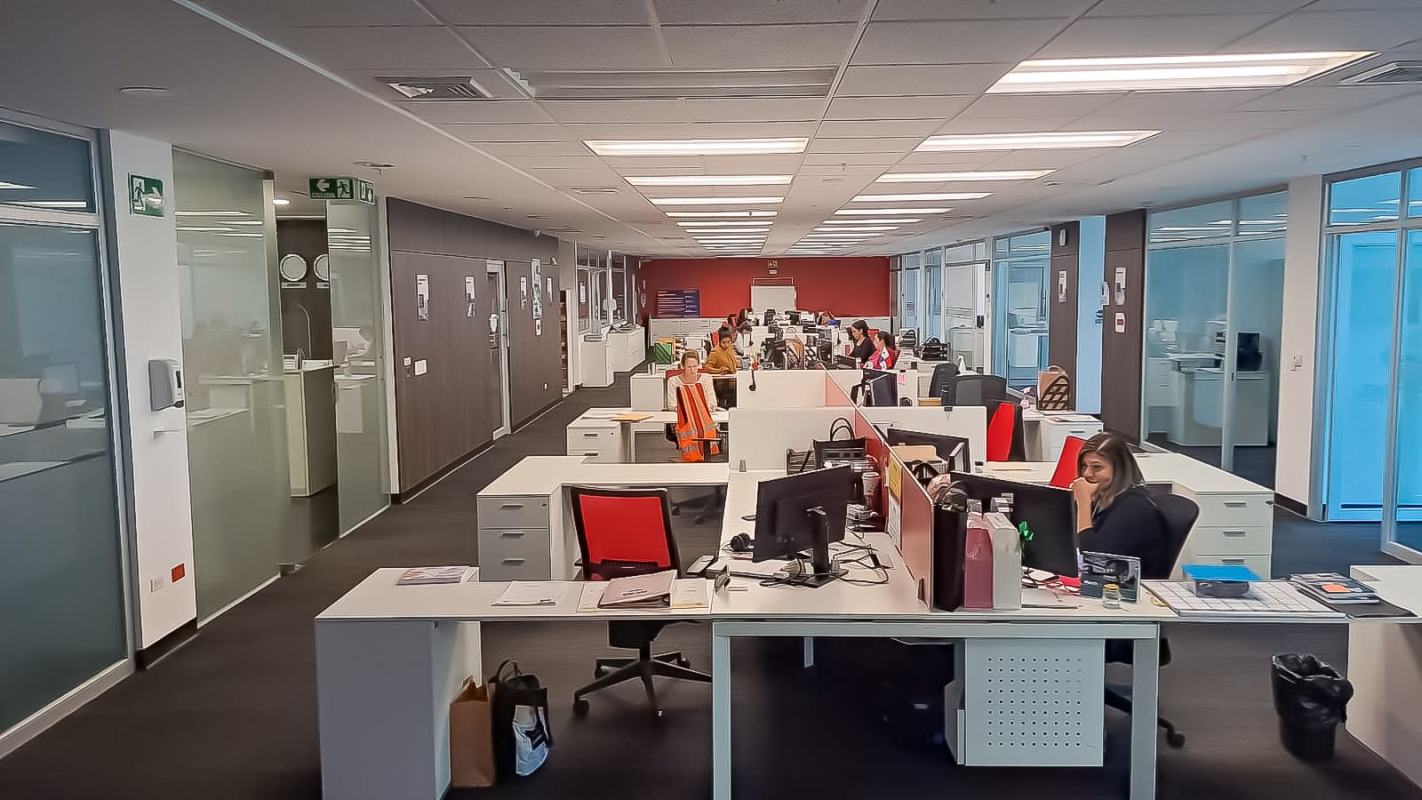 Modern open-plan office with cubicles, glass partitions, LED lights and employees at PH Plaza Real Panama City