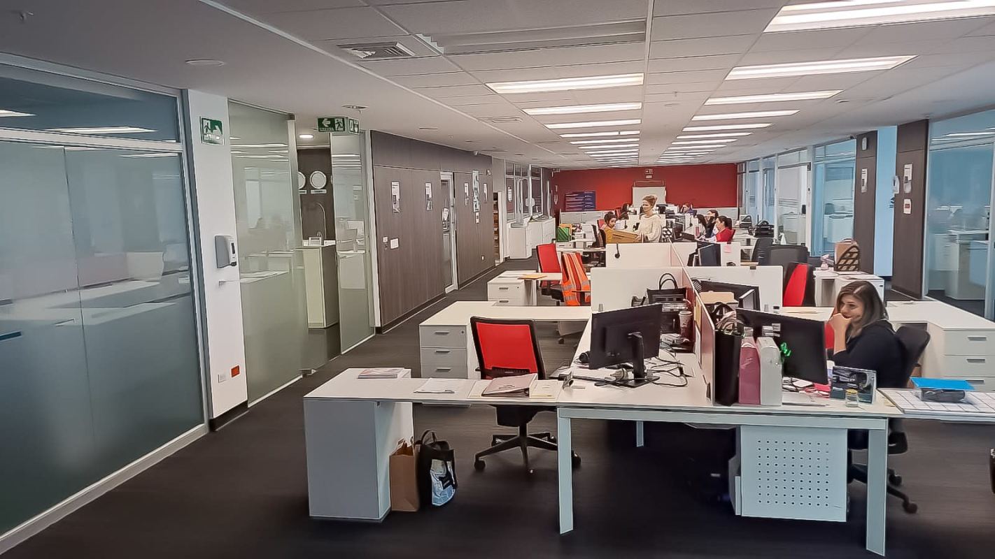 Spacious modern office workspace featuring glass partitions, multiple desks, red chairs in PH Plaza Real Costa del Este