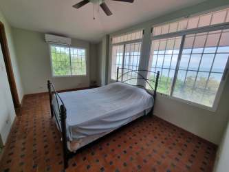 Simple bedroom with large window, tile flooring, ceiling fan, air conditioning and ocean view in Portobelo Panama