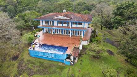 Aerial view two-story villa with terracotta roof, terrace, infinity pool amidst lush greenery Portobelo Panama