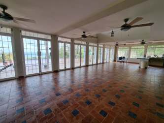 Bright enclosed patio with terracotta floor, large windows, ceiling fans in Portobelo estate Panama