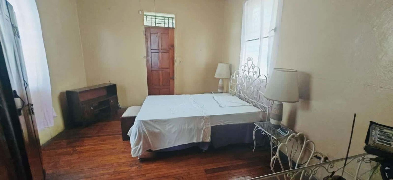 Traditional bedroom with wood floor metal bed high ceiling in multi-unit Panama complex
