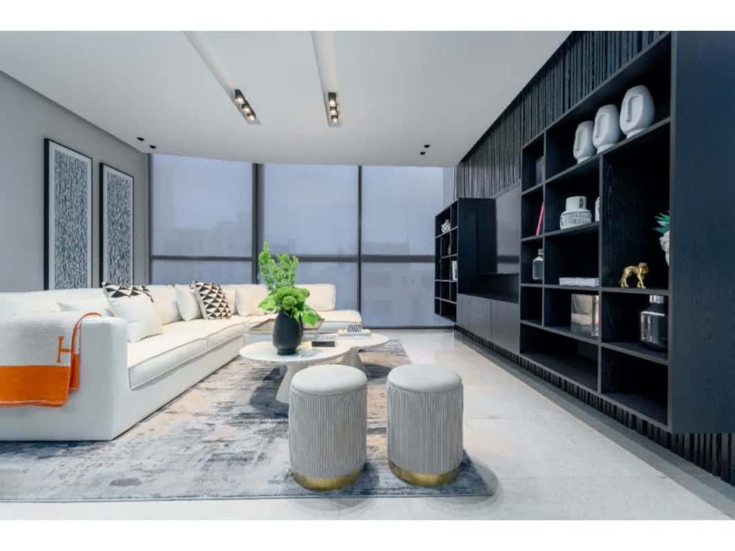 Living space with white sectional sofa, black shelving unit, and skyline view PH Deluxe Residences Paitilla Panama City