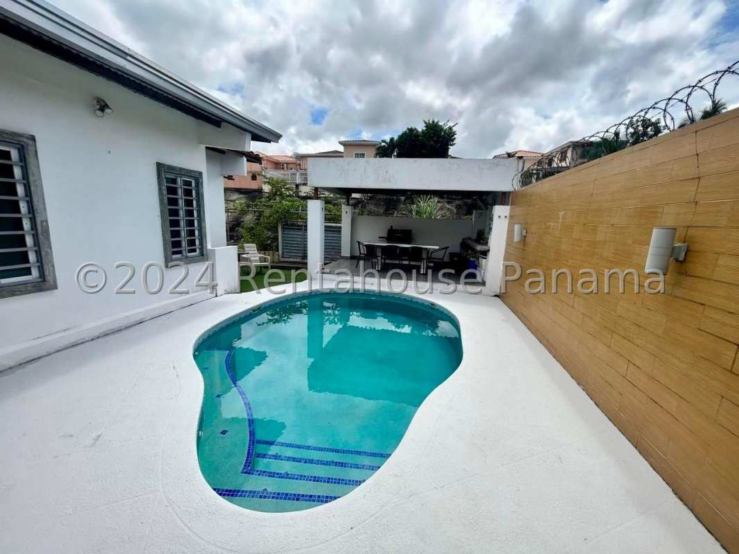 Covered outdoor dining next to pool with privacy wall in Condado del Rey Panama
