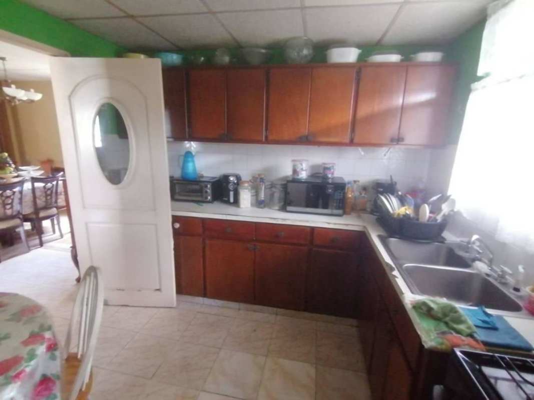 Kitchen with wood cabinets, white tile counter, adjacent dining area in Villa Zaita Panama