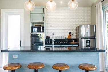 Modern kitchen with blue island, black countertop, subway tile backsplash, stainless appliances Villa 32 Playa Venao