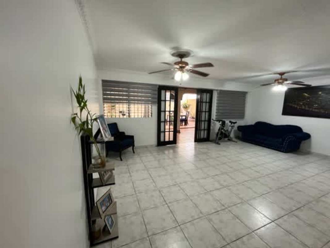 Large living-dining area with tile floors, ceiling fans, glass doors, blue sofa Limajo Panama City