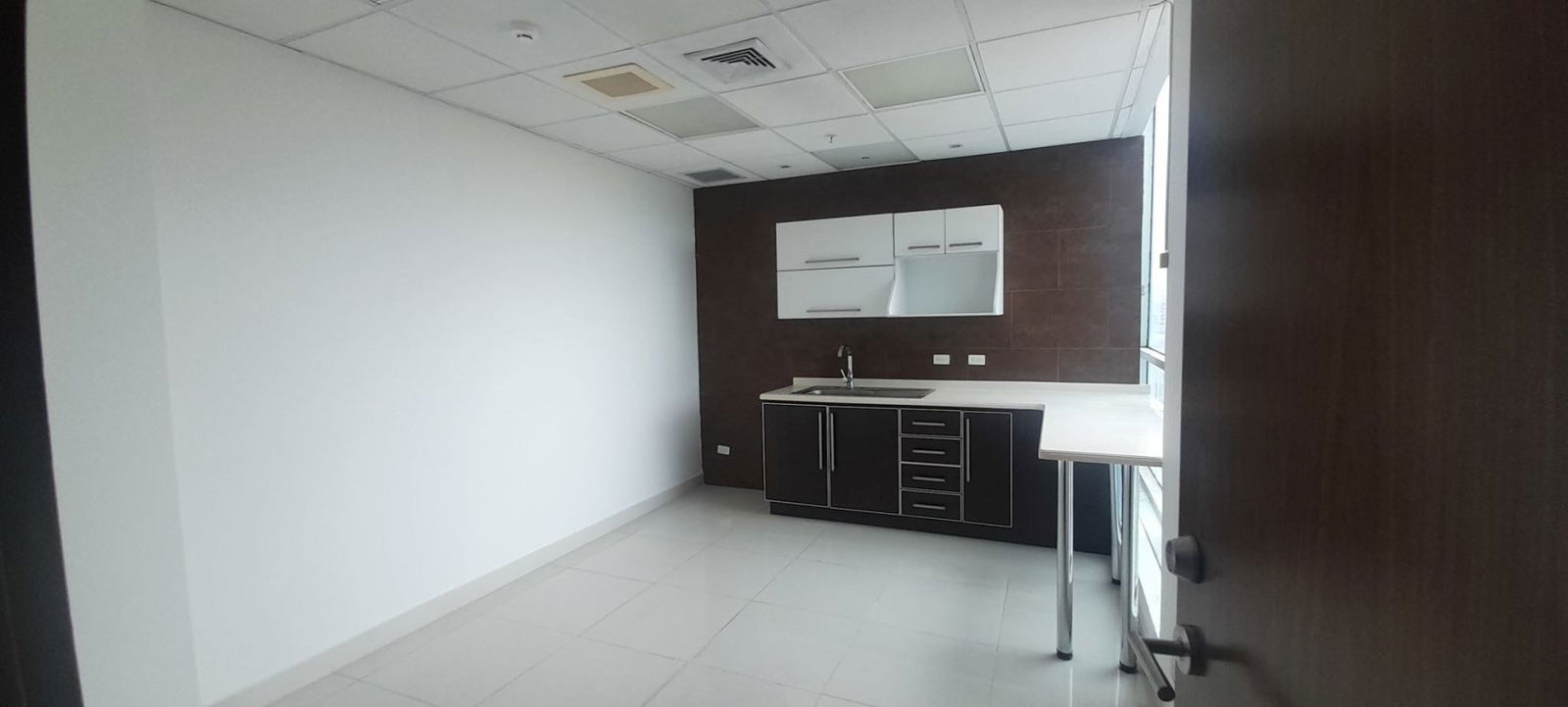 Compact kitchenette with sink and wood cabinets in commercial office Costa del Este Panama