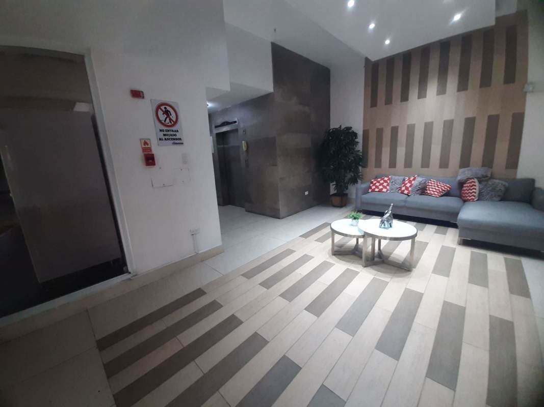 Apartment building lobby with sectional sofa, elevator access, striped floor and accent wall in PH Vista Marina Tower Panama City
