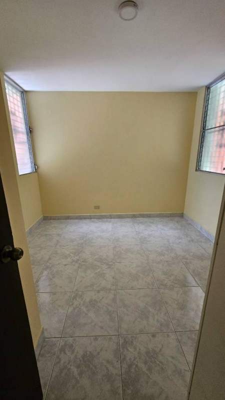 Minimalist bedroom with tiled floors, neutral walls and window louvers in Betania Panama