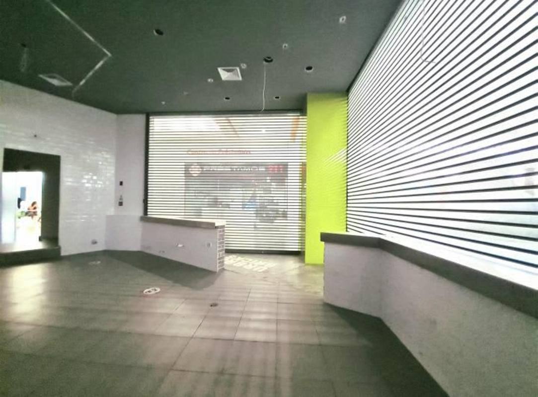 Retail space inside Albrook Mall with counter, tiled walls and floor, green accented wall