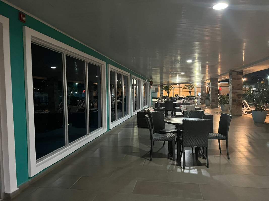 Covered outdoor terrace with wicker furniture and stone pillars in Brisas del Golf Panama