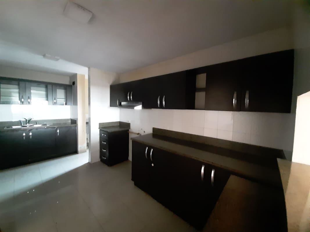 Spacious modern kitchen with granite countertops and upper/lower dark cabinetry in PH Del Rey apartment Panama City