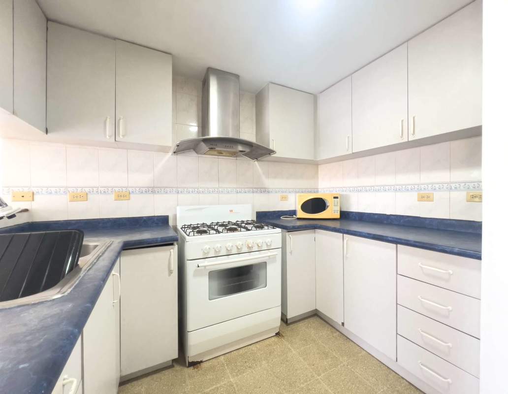 Open kitchen with white cabinets, blue countertops, stove in Destiny Tower Panama