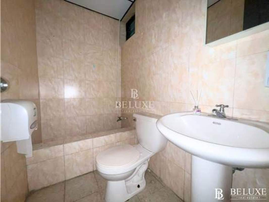 Simple bathroom with pedestal sink, wall-mounted mirror and tiled walls in PH El Dorado Panama