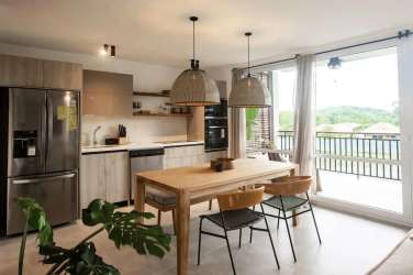 Modern kitchen dining open plan with wood accents pendant lights balcony view Playa Venao