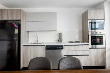 Open kitchen with modern cabinetry, appliances, wood dining table at Blue Venao Playa Venao