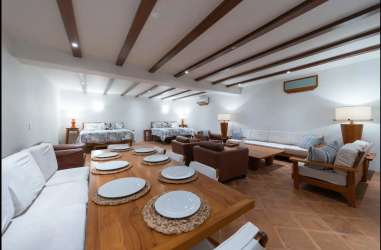 Open-plan living space with beds dining seating rustic beams Villa Quintet Destiladeros Pedasí Panama