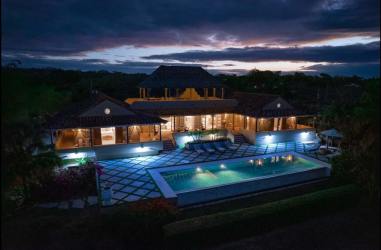 Evening aerial view of Mediterranean-style beachfront villa with illuminated pool and patio Villa Quintet Pedasí Panama