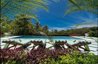 Infinity pool with palm trees lush gardens outdoor sunbeds Villa Quintet Los Destiladeros Pedasí Panama