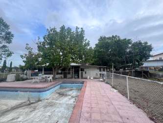 Main entrance of commercial lot with gravel driveway, metal gate, carport and parking Nueva Gorgona Panama