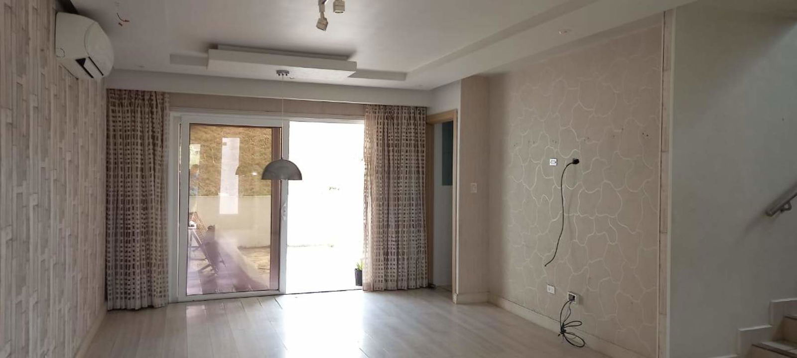 Bright living room with sliding glass doors, staircase, air conditioning bracket in duplex house Brisas del Golf Panama