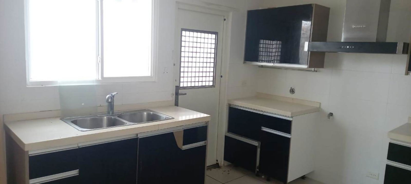 Modern kitchen with cabinetry, double sink, window and tiled backsplash in PH Victoria Brisas del Golf Panama
